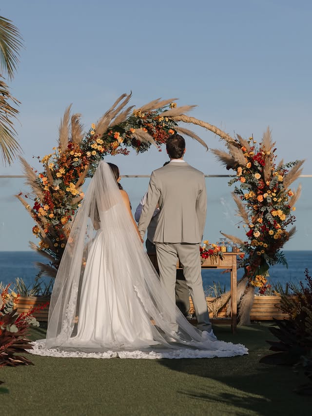Cerimônia de casamento com arco floral à beira-mar